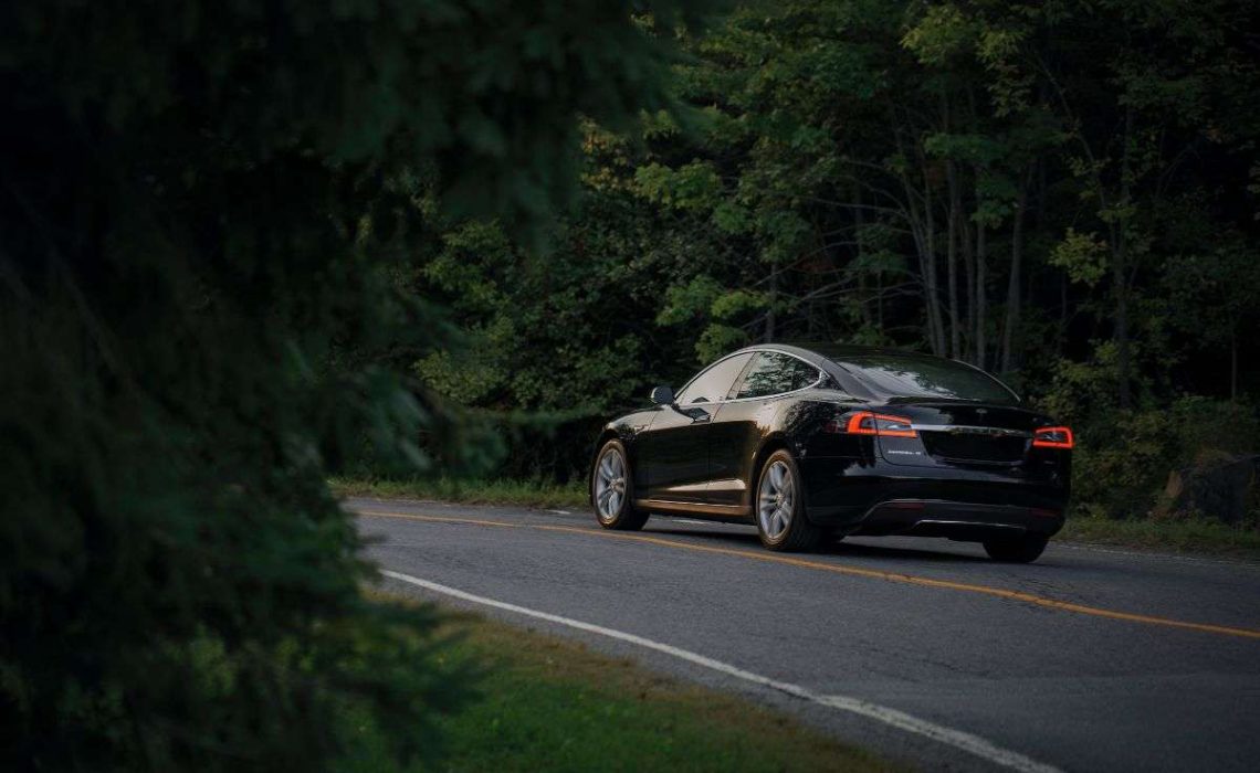 An electric car drives through the forest in Canada. Photo by Jp Valery.